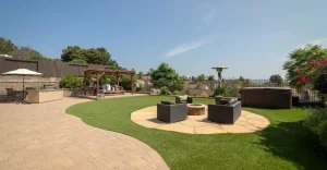 Backyard with lawn, seating area, fire pit, pergola, and surrounding greenery