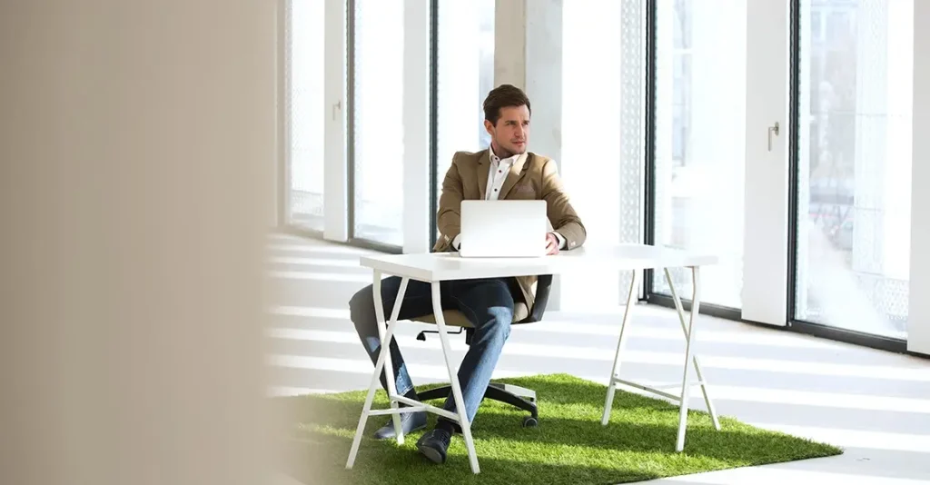 Man sitting at a desk with a laptop in a bright, spacious room