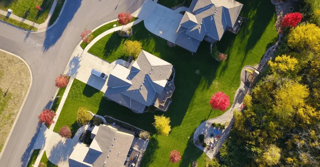 Aerial view of residential homes with green lawns and colorful trees