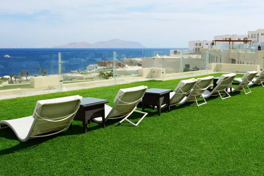 Lounge chairs arranged on a green lawn with a view of the ocean and distant islands