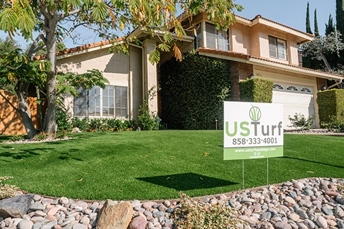 House with landscaped yard, green grass, and a sign in front with contact information