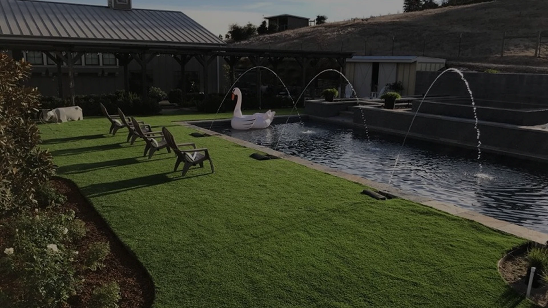 Backyard with a pool, lawn chairs, and a large swan-shaped float in the water