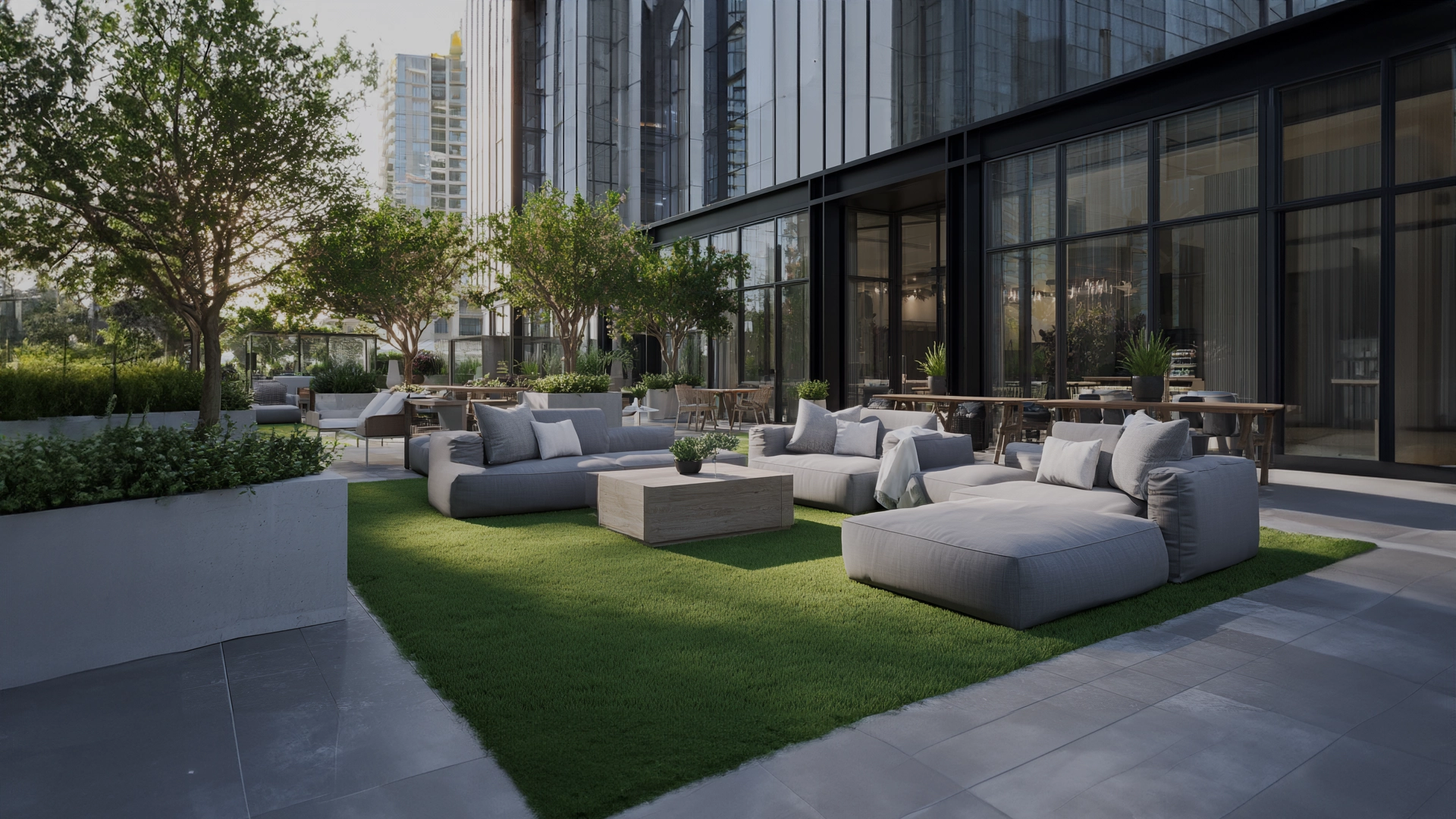 Outdoor lounge area with seating on grass and greenery near a modern building