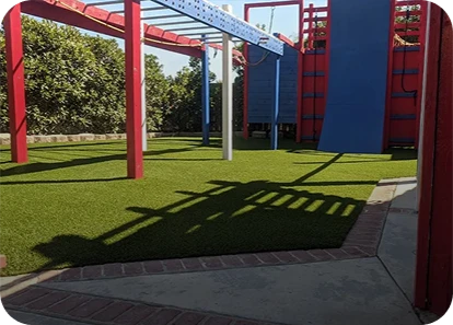 Playground structure with red frames, blue climbing wall, and grassy surface