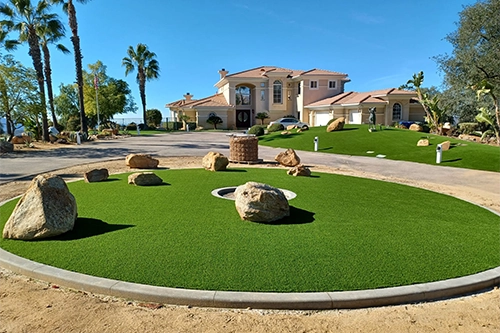 A residential property with a green lawn, rocks, and palm trees in the foreground