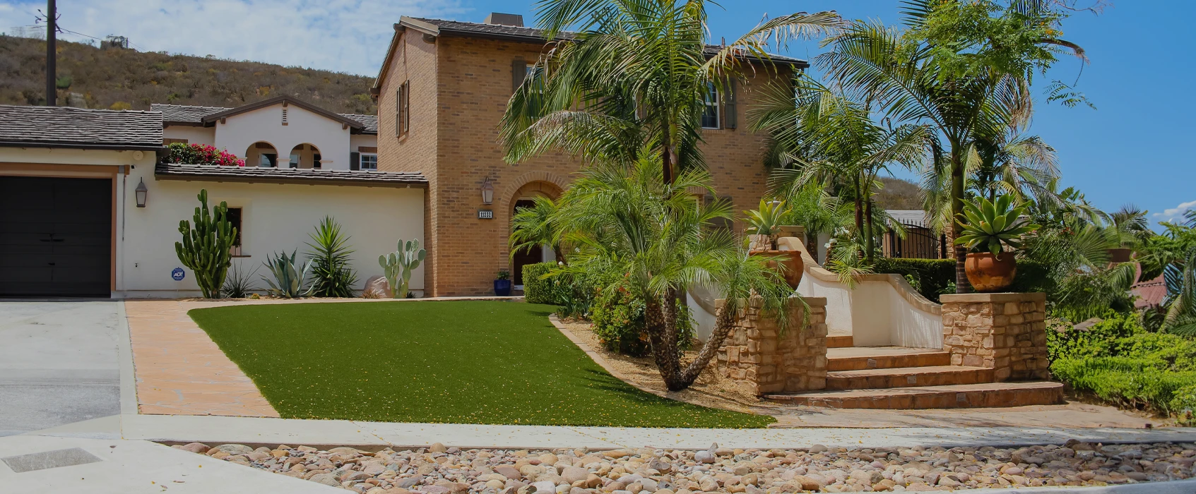 Exterior view of a two-story home with palm trees and a landscaped yard