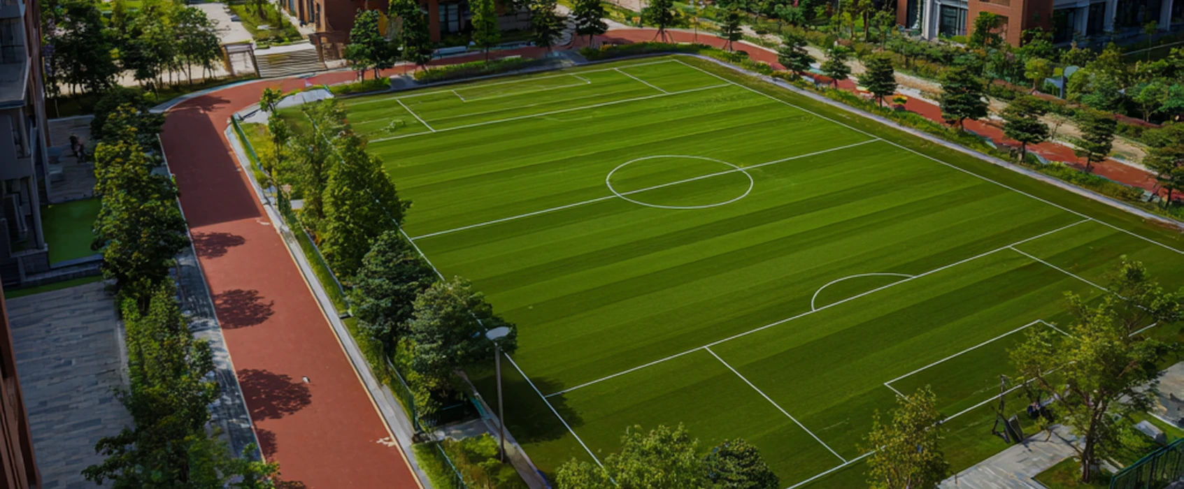 Aerial view of a green soccer field surrounded by trees and pathways
