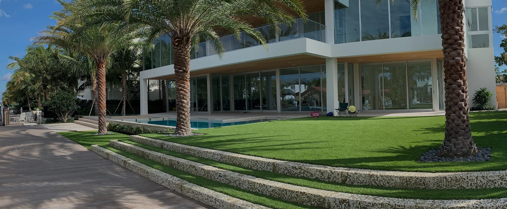 Modern house with large windows, palm trees, a lawn, and a swimming pool
