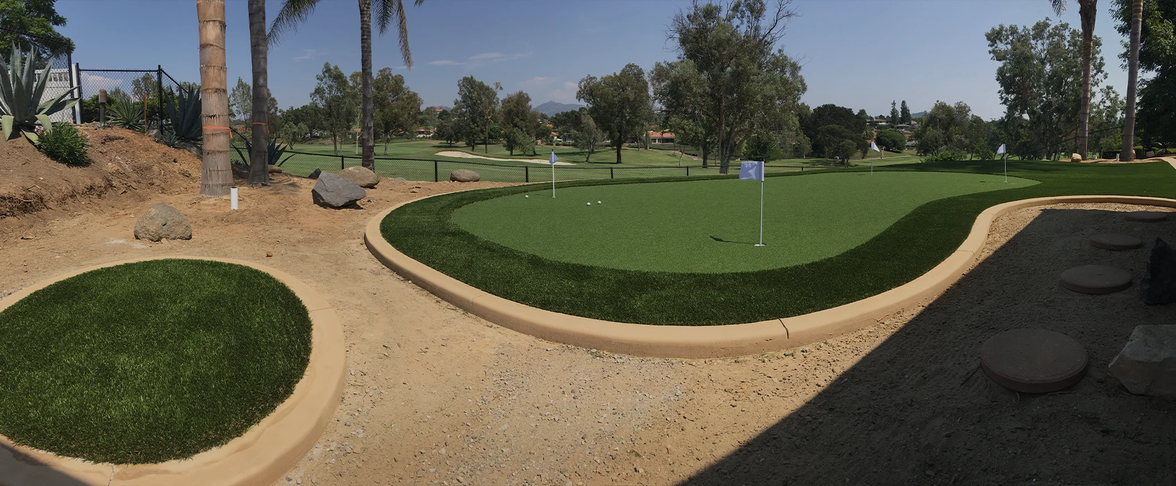 Panoramic view of a golf putting green surrounded by grass and trees