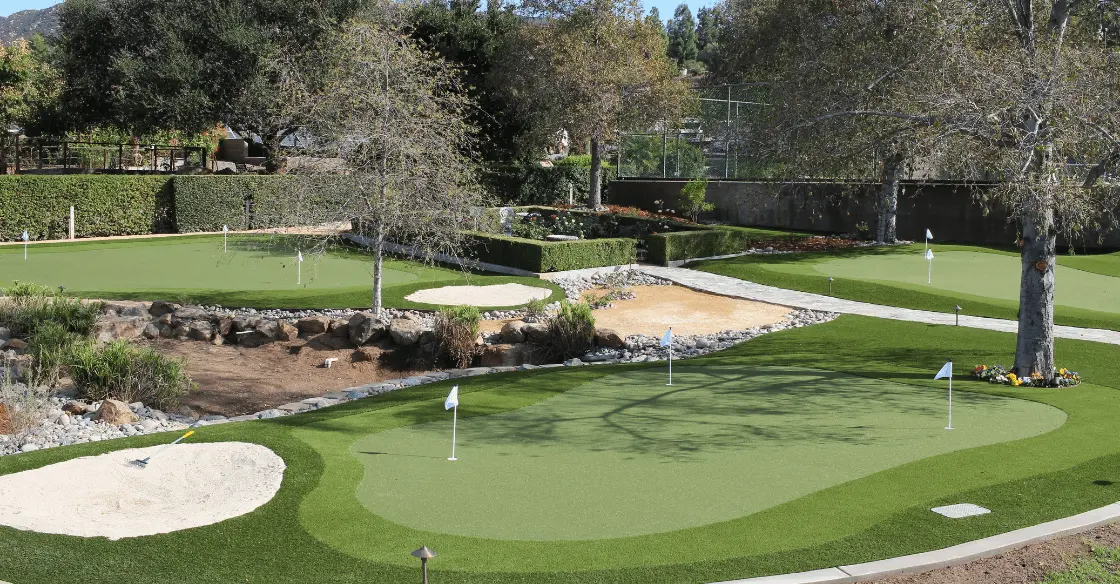 Golf course with several putting greens, sand traps, and landscaped areas