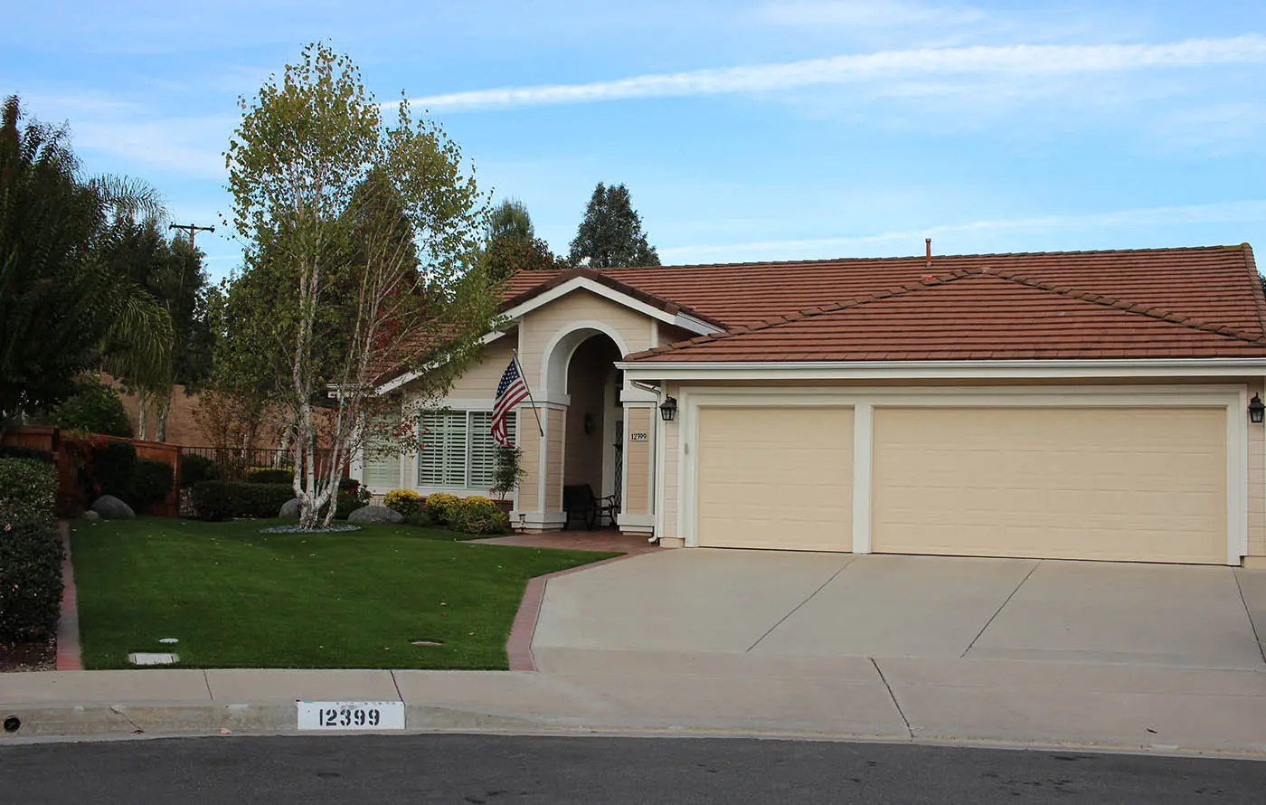 Single-story house with a red tile roof, green lawn, and a driveway