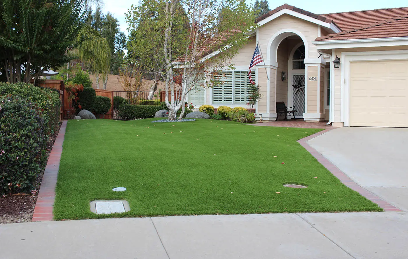 A house with green grass in the front yard and an American flag by the entrance