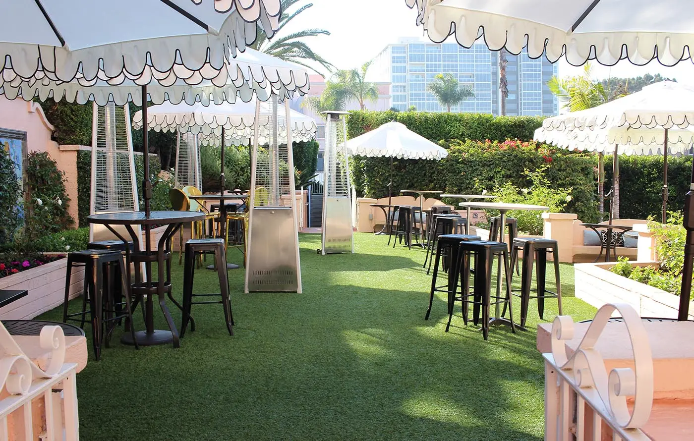 Outdoor seating area with tables, chairs, and umbrellas on green grass