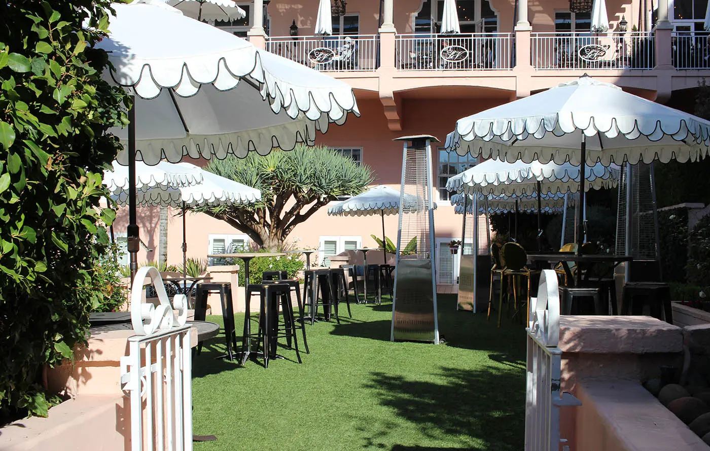 Outdoor seating area with green grass, tables, and large umbrellas