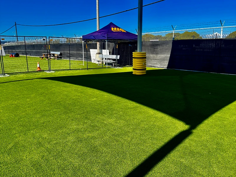 Open green space with artificial turf and a shaded tent in the background