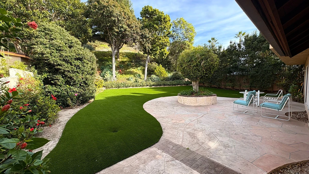 A landscaped garden with a curved pathway, green grass, and a seating area