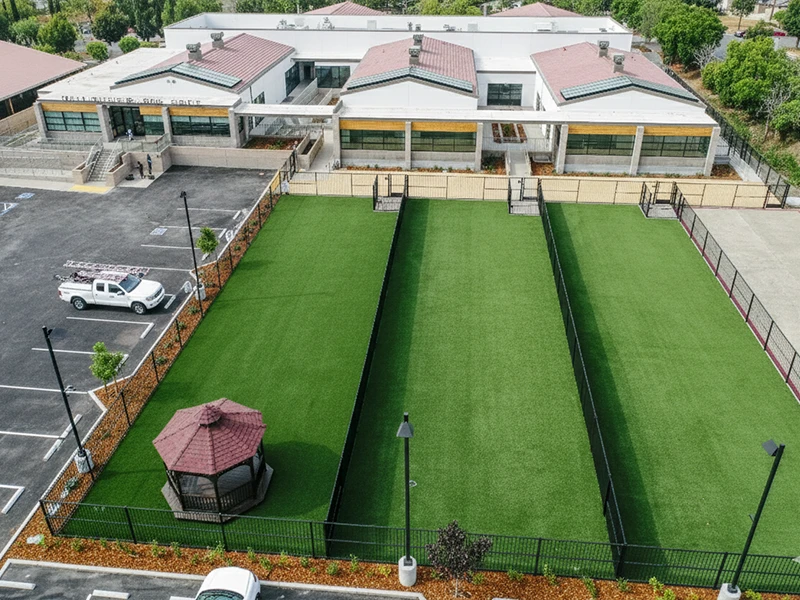 Aerial view of a green turf area with a gazebo and a building in the background
