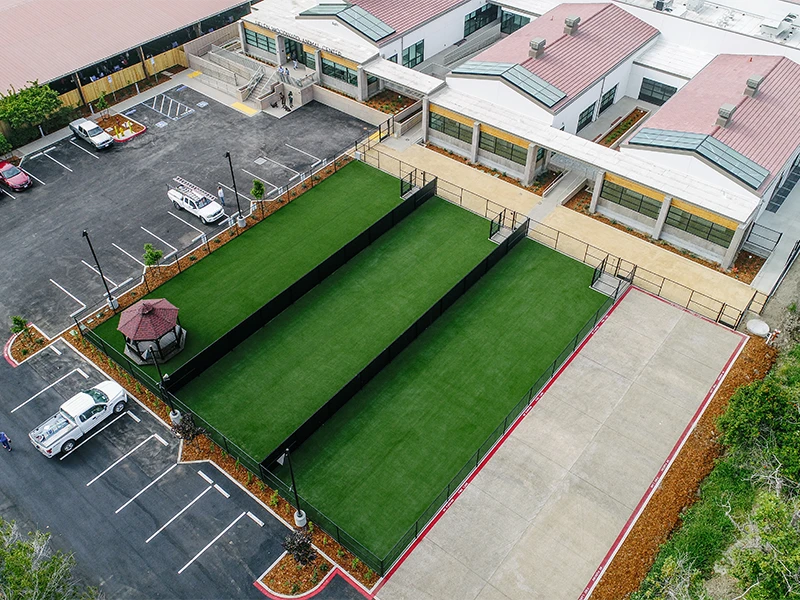 Aerial view of a building with green lawns, a gazebo, and a parking lot