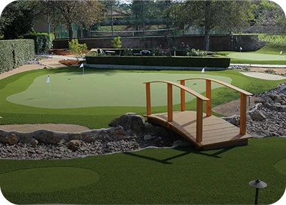 A landscaped putting green with a wooden bridge and stone features