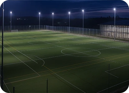 Well-lit soccer field at night with goalposts and surrounding fencing