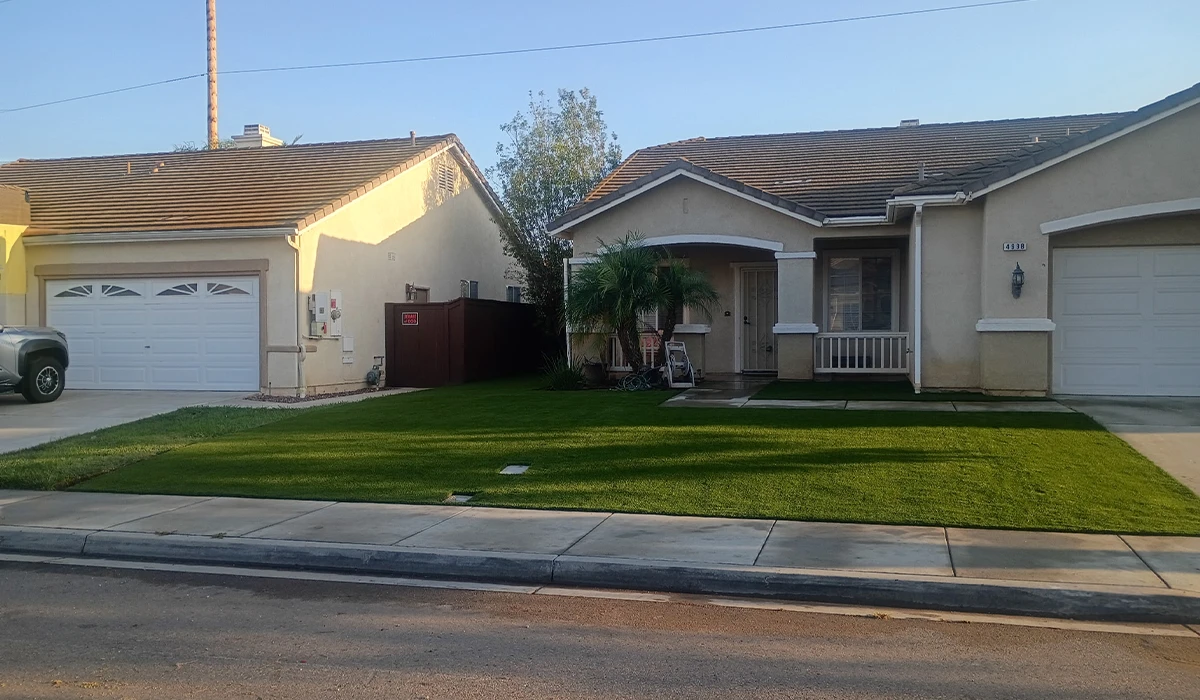Two single-story houses with lawns, one with a porch and palm tree, and a driveway