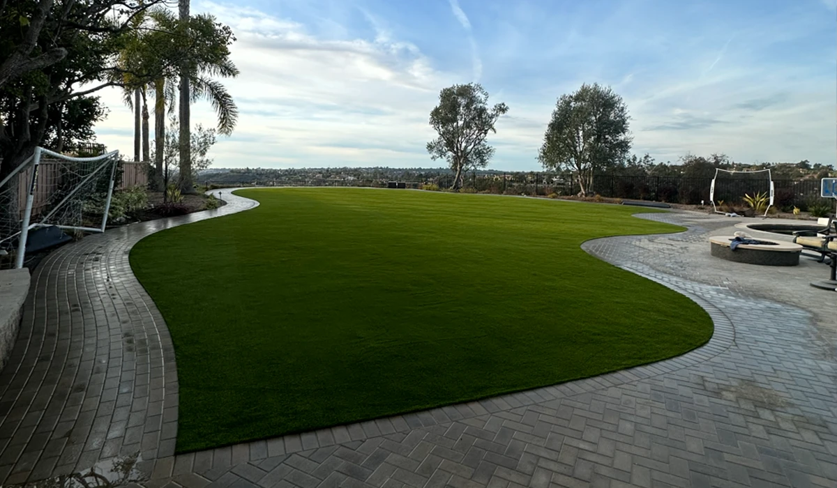 Green lawn with curved stone path, trees, and cloudy sky in the background