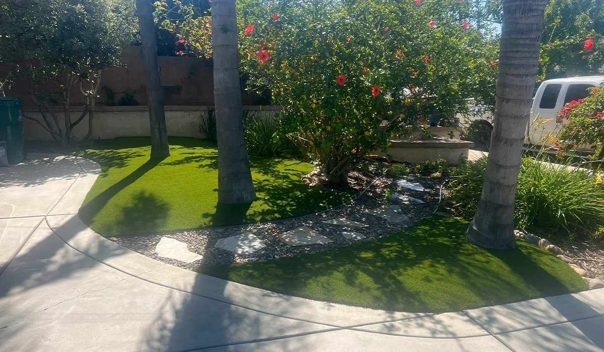 Lawn area with bushes and trees, curved sidewalk, and a white vehicle in the background