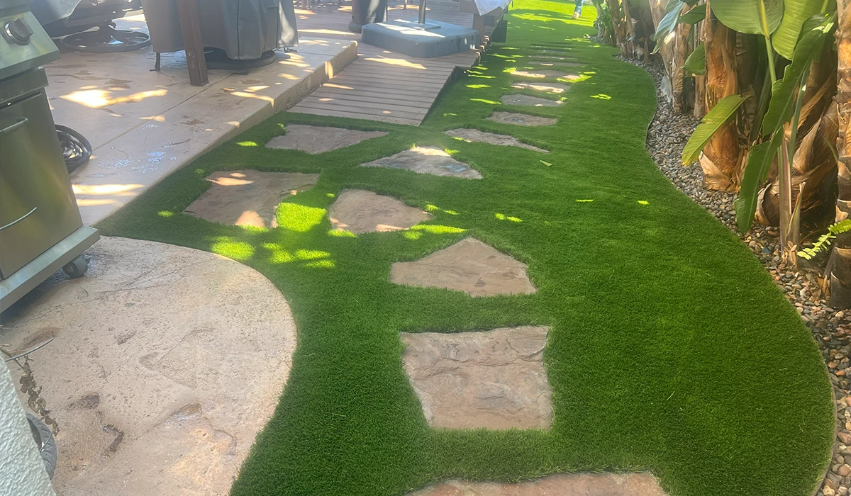 Pathway of stone tiles on green grass, surrounded by plants