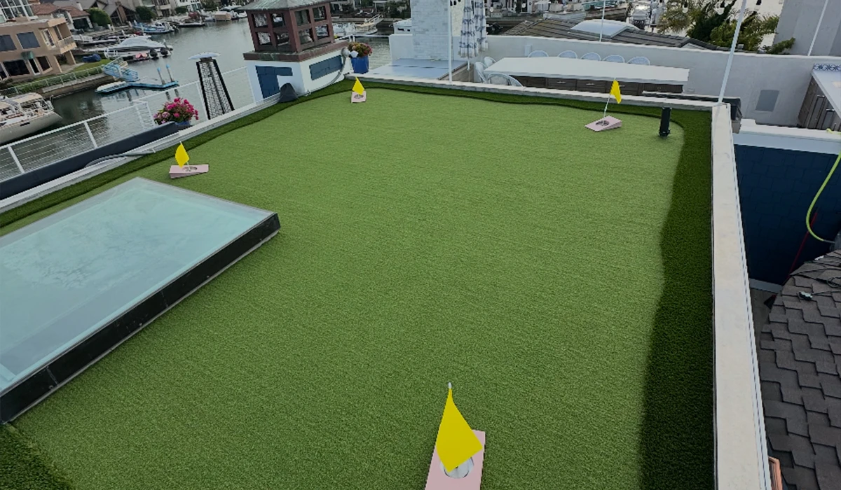 Rooftop area with artificial grass and small yellow flags, overlooking a marina