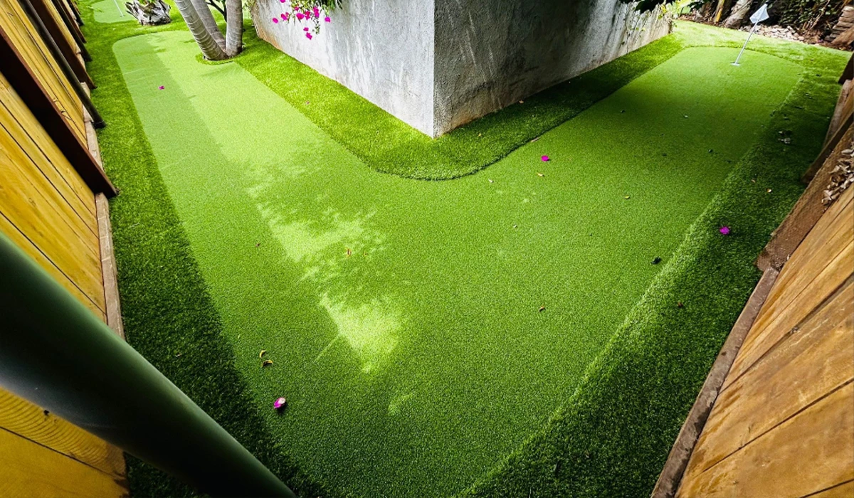 Artificial grass path winding around a building with plants above