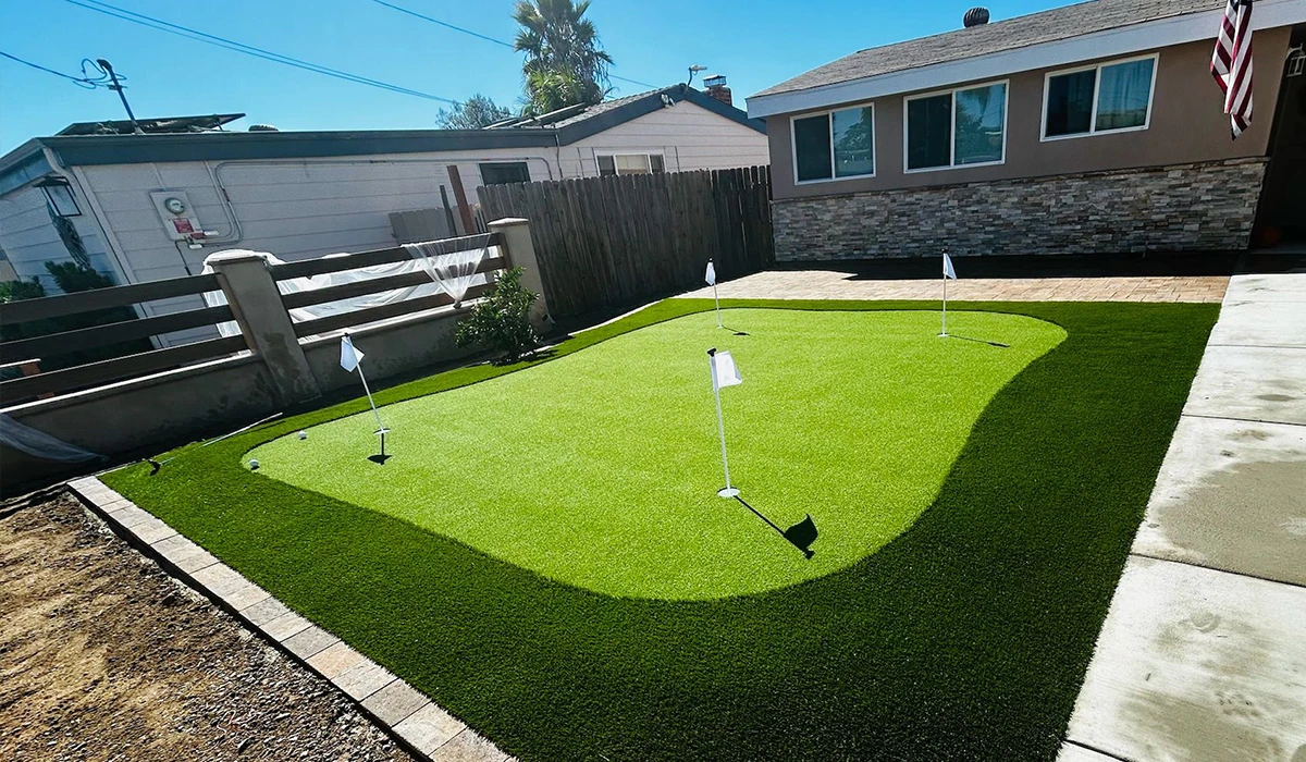 Artificial grass putting green with four flags in a backyard setting