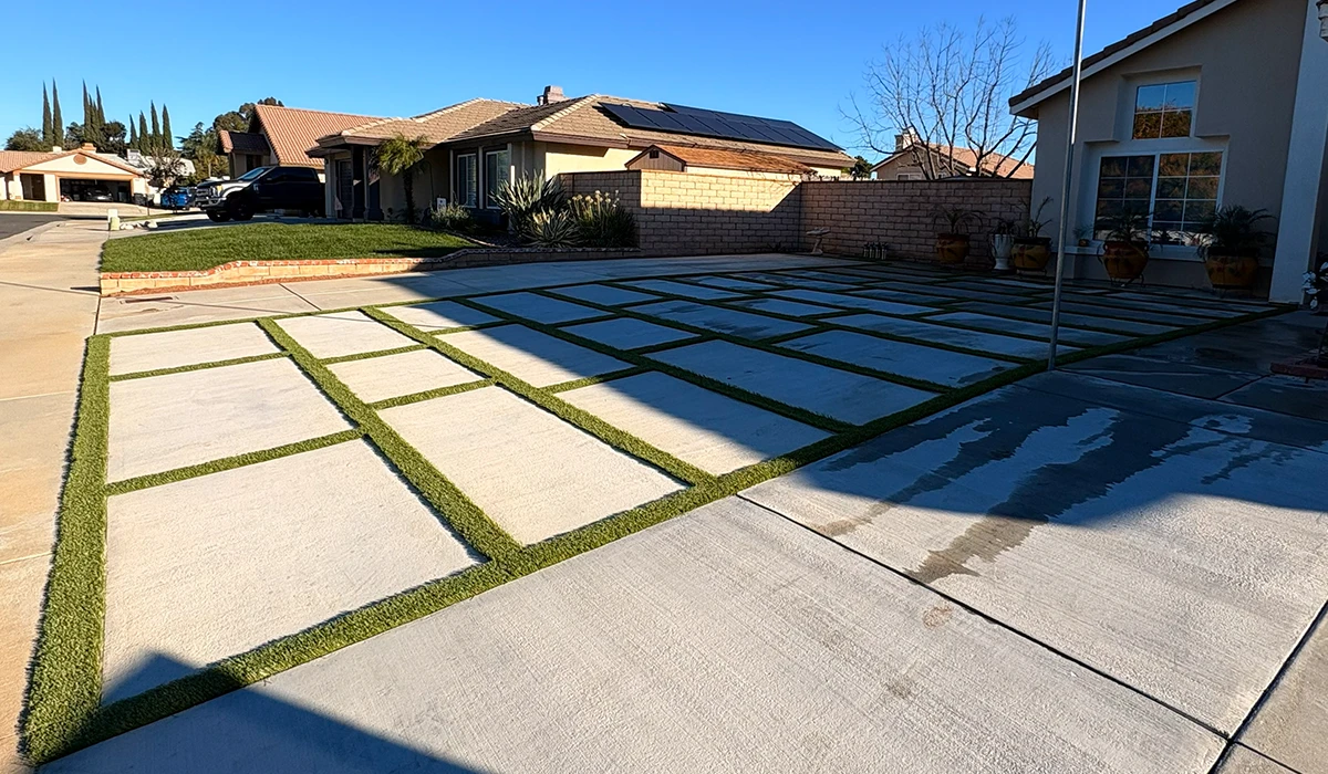 Concrete driveway with grass patches arranged in a grid pattern beside a house