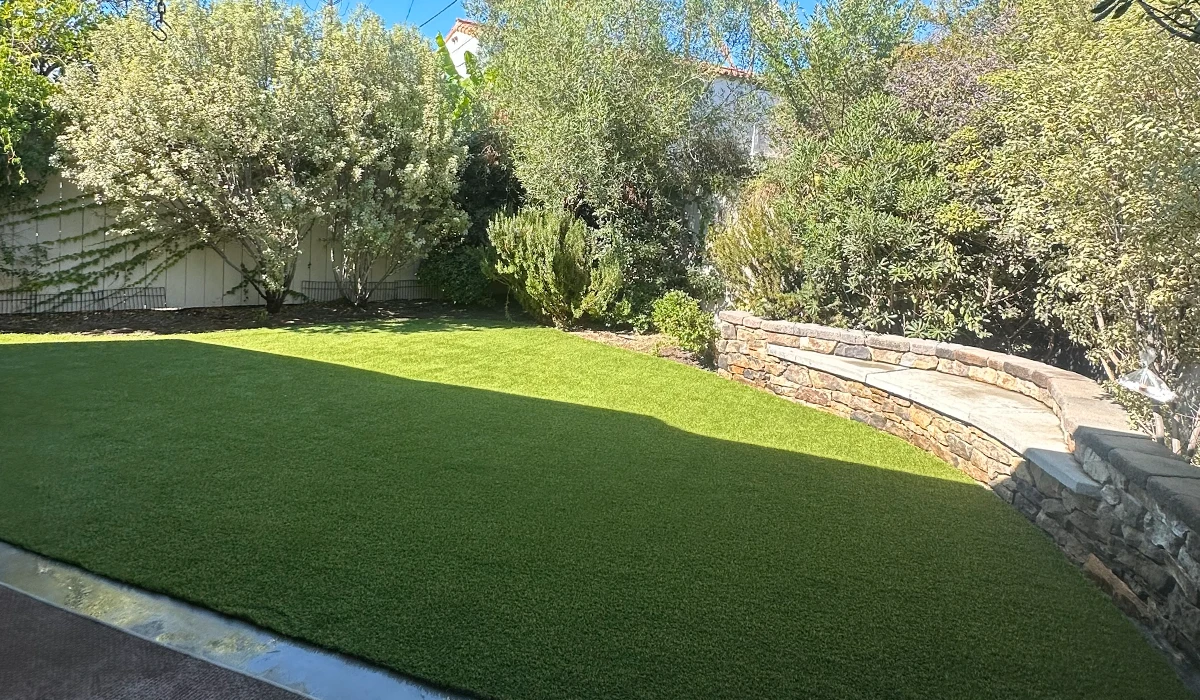 View of a landscaped yard with grass, trees, and a stone step area