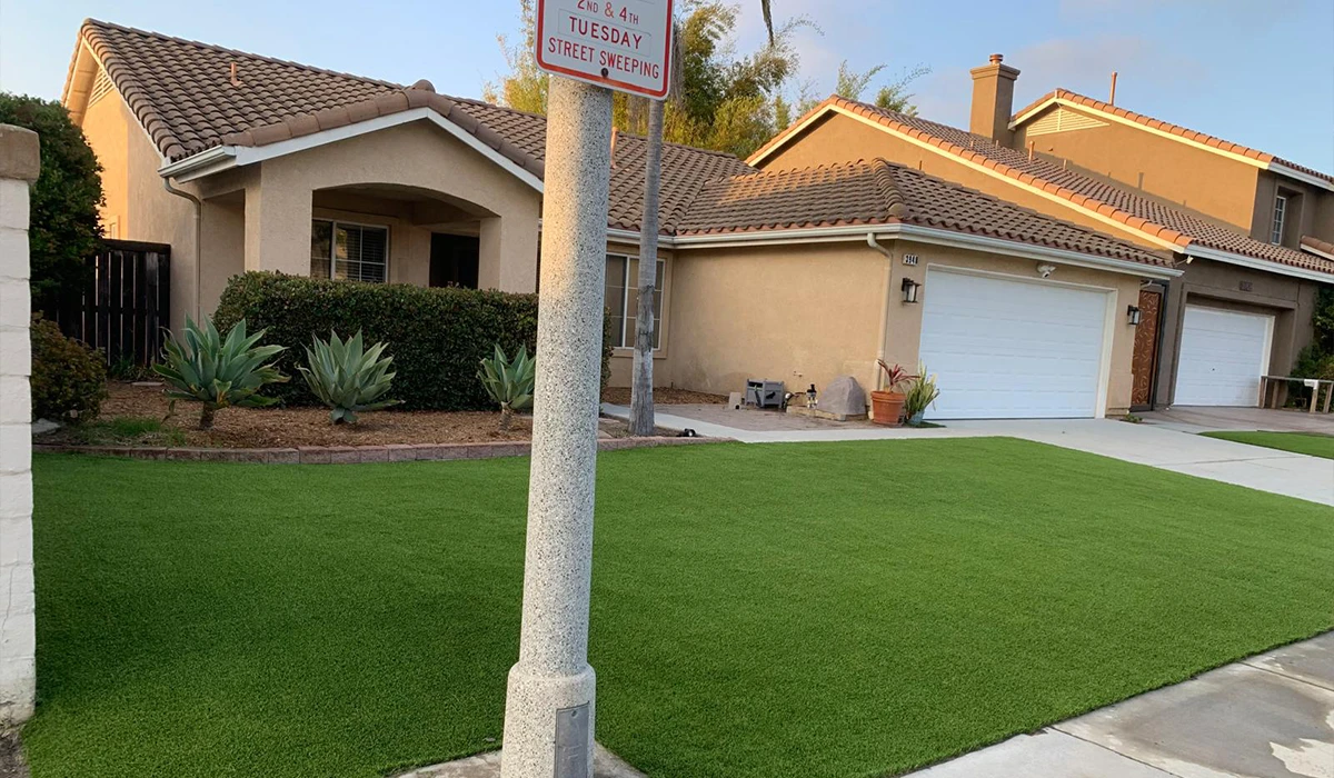 Front yard of a house with green grass, a signpost, and a garage