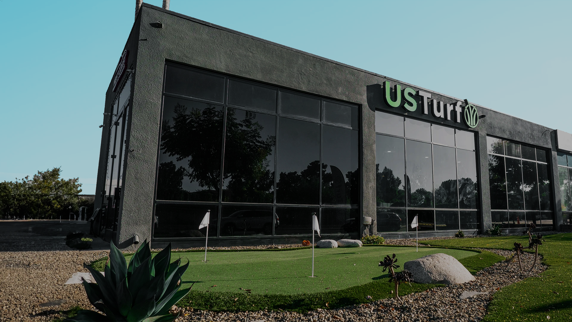 Exterior of a building with large glass windows and a small putting green in front