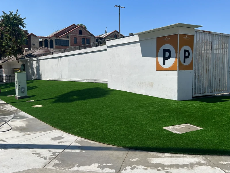 Parking area with green turf and a white wall marked with a 'P' symbol