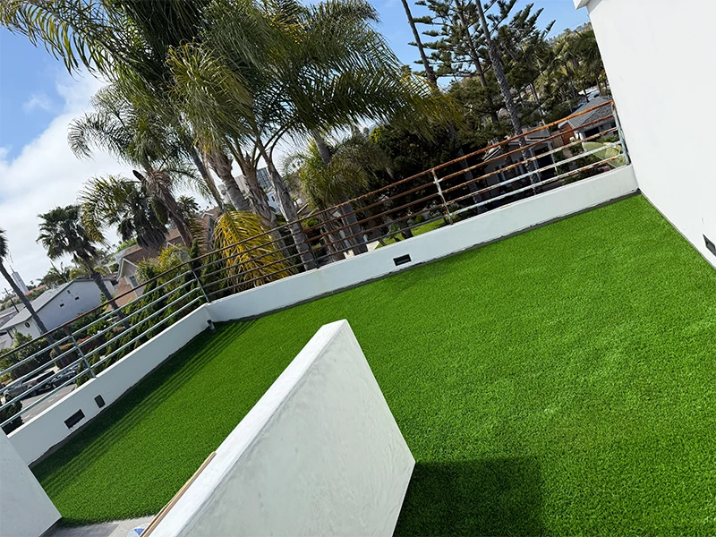 View of a rooftop terrace with artificial grass and palm trees in the background