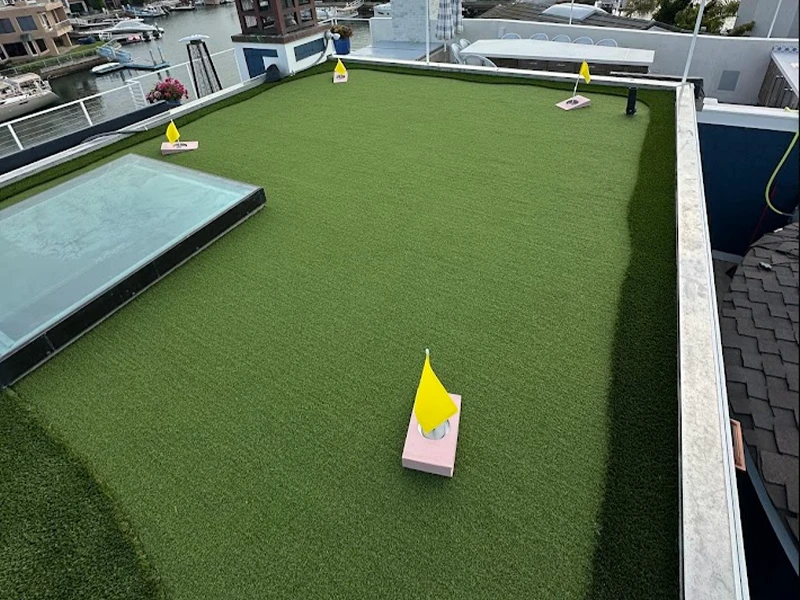 Rooftop area with artificial grass, small yellow flags, and a shallow pool