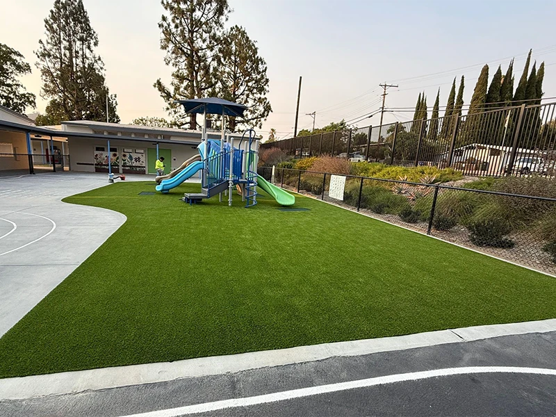 Playground with a blue slide and climbing structure on green artificial turf